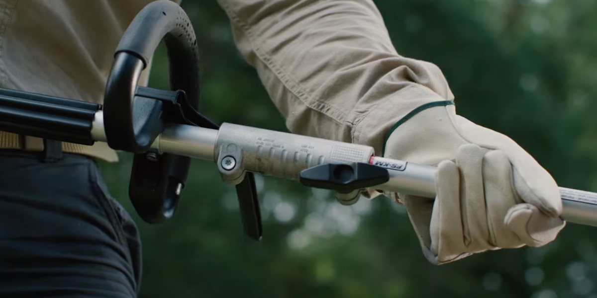 close-up image of a hand holding a stihl kombisystem attachment as they lock it into place