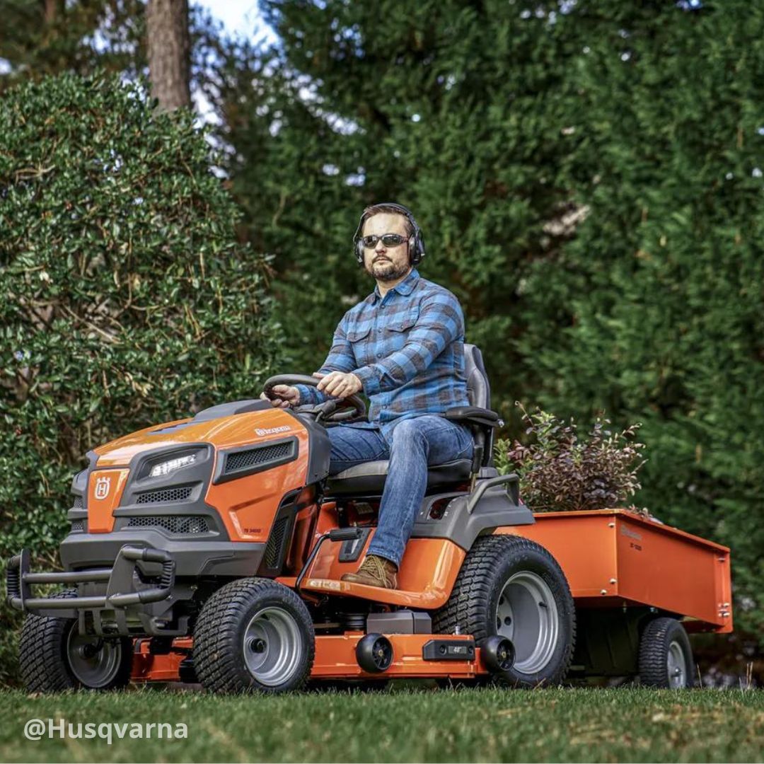 Man driving Husqvarna lawn tractor and towing trailer