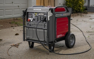 The Honda EM7000iS generator outside with debris from a storm on the ground