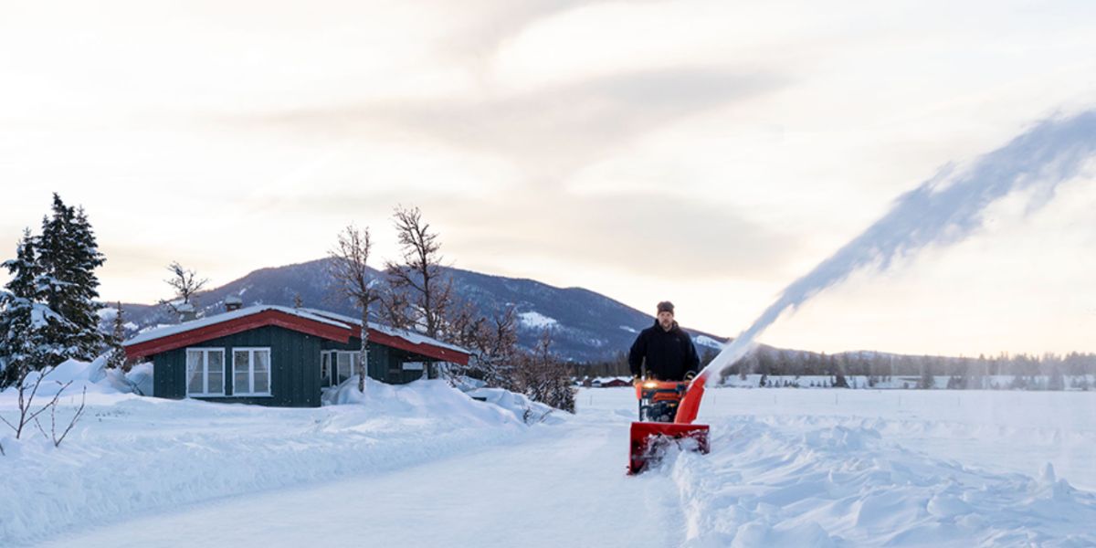 Man outside on a snowy day using an Ariens Deulxe snow thrower