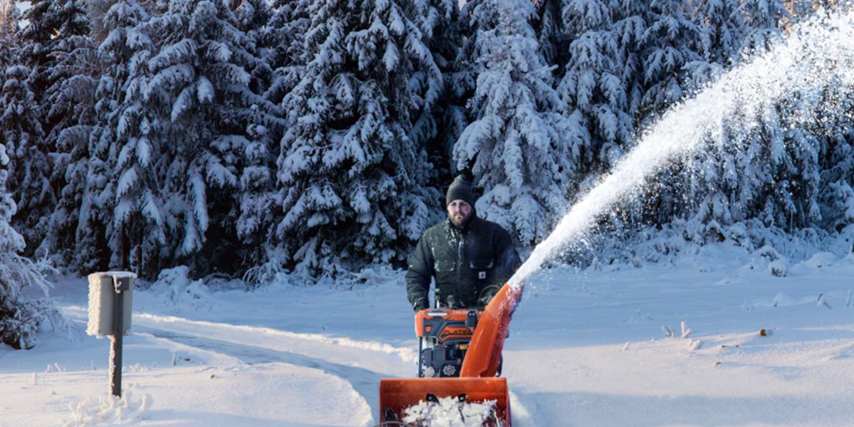 Man outside on a snowy day using an Ariens Platinum snow thrower