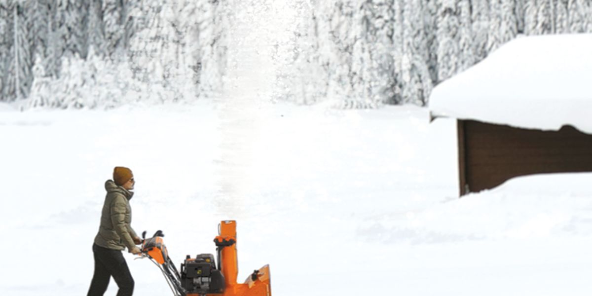 Man outside on a snowy day using an Ariens RapidTrak snow thrower